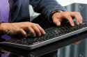 15933519-man-s-hands-working-on-computer-keyboard