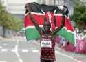 skinny marathon runner eliud-kipoghe-in-tokyo-raising-flag