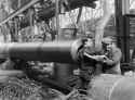 A female worker is lifted into the barrel of a 15-inch gun in order to clean the rifling in the Coventry Ordnance Works during the First World War..jpg