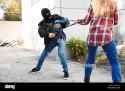 male-thief-stealing-bag-from-young-woman-outdoors-T9BC8C