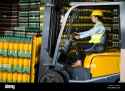 side-view-of-confident-female-worker-driving-forklift-in-warehouse-HWFKCX