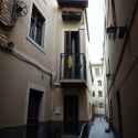 Precise architectural color photography. Anine style, exterior view of a humble apartment with a terraza on a dead-end alley. Sharp lines, detailed structures, wide angles, diffused shadows, subtle illumination. 