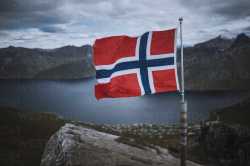 norway-senja-norwegian-flag-with-fjord-and-mountains-in-background-TETF00774