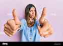 brunette-young-woman-doing-thumbs-up-positive-gesture-clueless-and-confused-expression-doubt-concept-2E8G539