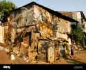 mother-and-child-enter-their-ramshackle-shack-like-house-in-slum-areasurabayajavaindonesia-A87YMT