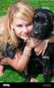 young-white-blond-woman-girl-with-hugging-her-black-labrador-puppy-BBJC1G